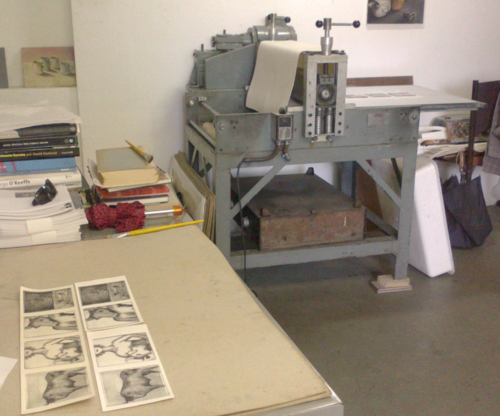 a prensa ao fundo com as gravuras impressas secando.